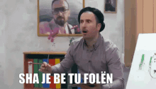 a man in a beret is holding a brush in front of a white board with the words sha je be tu folen above him
