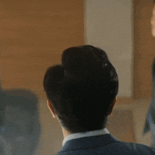the back of a man 's head is shown in a close up . he is wearing a suit and tie .