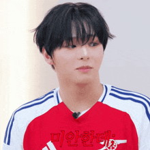 a young man wearing a red and white shirt with korean writing on it