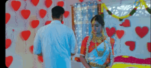 a man and a woman are standing next to each other in a room decorated with balloons and hearts .