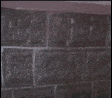 a man with a mustache is leaning against a brick wall .