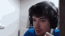 a man wearing headphones and a blue shirt is eating a piece of chocolate .