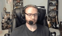 a man wearing headphones and glasses is sitting in a chair with a microphone .
