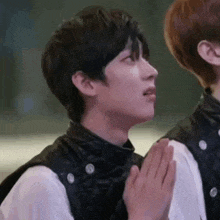 a man in a leather vest is praying with his hands together .