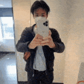 a man wearing a face mask is taking a picture of himself in a mirror .