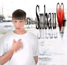 a young man in a white shirt is standing in front of a sign that says snbau
