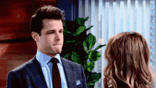 a man in a suit and tie looks at a woman in a blue shirt