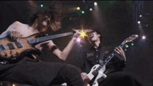 a shirtless man playing a guitar next to a man playing a guitar