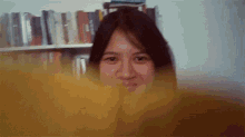 a woman is smiling in front of a bookshelf filled with books .