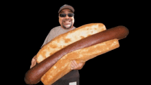 a man wearing sunglasses is holding a large hot dog