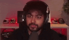a man with a beard wearing headphones is sitting in front of a table with helmets on it .