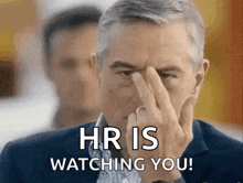 a man is covering his face with his finger and says hr is watching you
