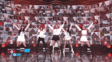 a group of girls are dancing on a stage in front of a wall of pictures with the words simply kpop on it