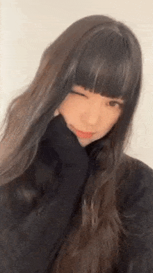 a girl with long hair and bangs is wearing a black turtleneck sweater and making a funny face .