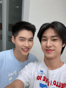 two young men are posing for a picture with one wearing a white shirt that says hello