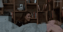 a person is laying in bed with a blanket and a sign that says youngertv