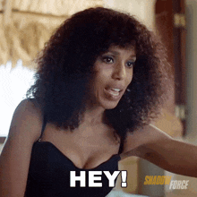 a woman with curly hair is saying " hey "