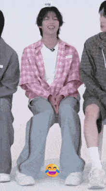 a man in a pink plaid shirt is laughing while sitting next to two other people