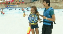 a man and a woman are standing next to each other in a pool .