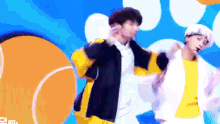 two young men are dancing on a stage in front of a blue background .