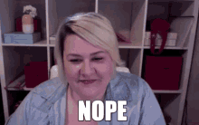 a woman is sitting in front of a shelf with the word nope on her face