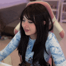 a woman wearing a blue and white shirt with the word swag on it sits in a pink chair