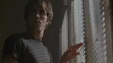 a man in a black shirt looking out a window