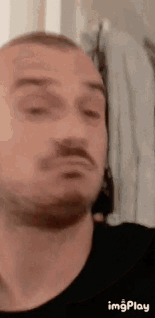 a man with a beard is looking at himself in the mirror and making a funny face .
