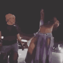 a woman in a purple dress is dancing with another woman in a black shirt