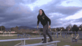 a man in a black hoodie is jumping over a bench