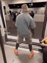 a man wearing a hat and shorts is standing in a doorway with a picture of him on the bottom