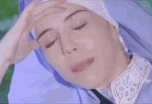 a woman in a nun costume is holding her forehead .