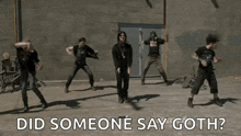 a group of people are dancing in front of a brick wall with the words " did someone say goth " above them