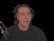 a man wearing headphones is making a funny face while sitting in front of a microphone .