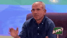 a man sitting on a couch with a sign that says apm