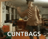 a man wearing a striped tie is dancing in a living room with the words cuntbags written on the bottom