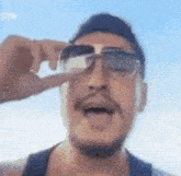 a man with a beard is wearing sunglasses and making a face .