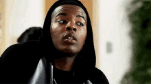 a close up of a man wearing a black hoodie and a black shirt .