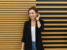 a woman stands in front of a wooden wall