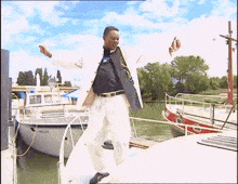 a man is standing on a boat with his arms outstretched in front of boats