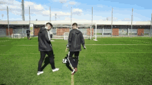 two men are playing soccer on a field and one is kicking a soccer ball