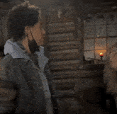 a woman is standing in front of a window with a candle in it and says " what " .