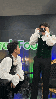 a man in a green vest takes a picture of another man