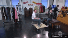 a man in a wheelchair is playing a video game in a store with other people .