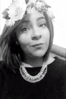 a woman wearing a necklace and a flower crown on her head .
