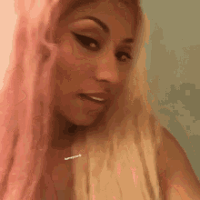 a close up of a woman 's face with pink hair and a necklace on her neck .