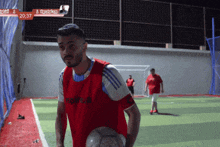a man in a red adidas jersey holds a ball