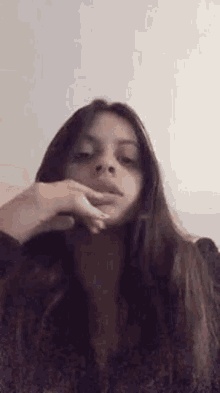 a woman with long hair is making a funny face with her hand on her face .