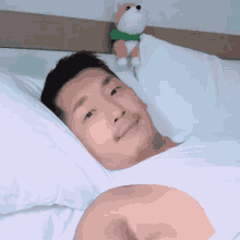 a man is laying in a bed with a stuffed dog on his head .