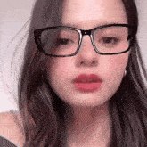 a close up of a girl wearing glasses and red lipstick .